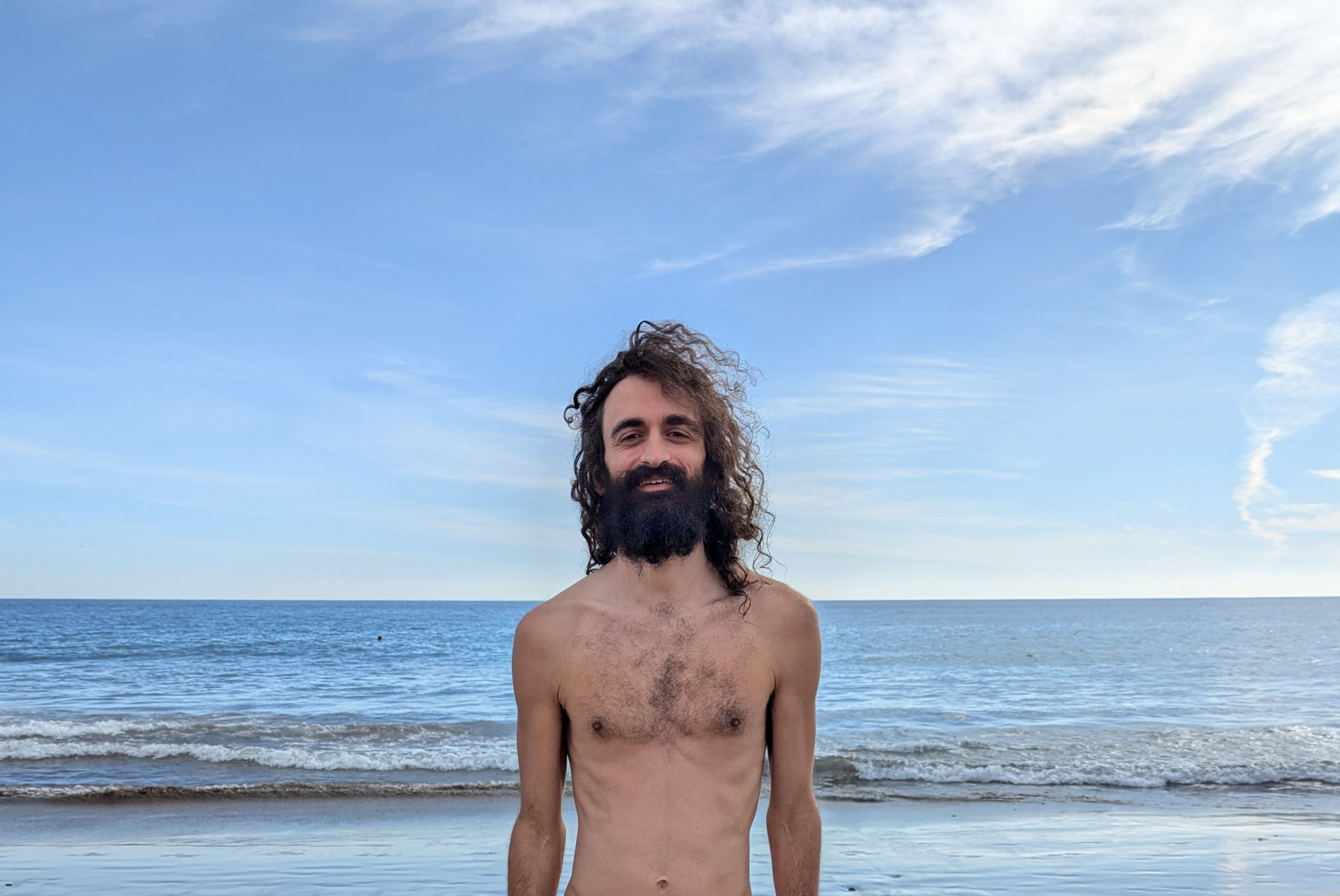 Me, Luca (Vivi), smiling on a beach with the sea and sky in the background